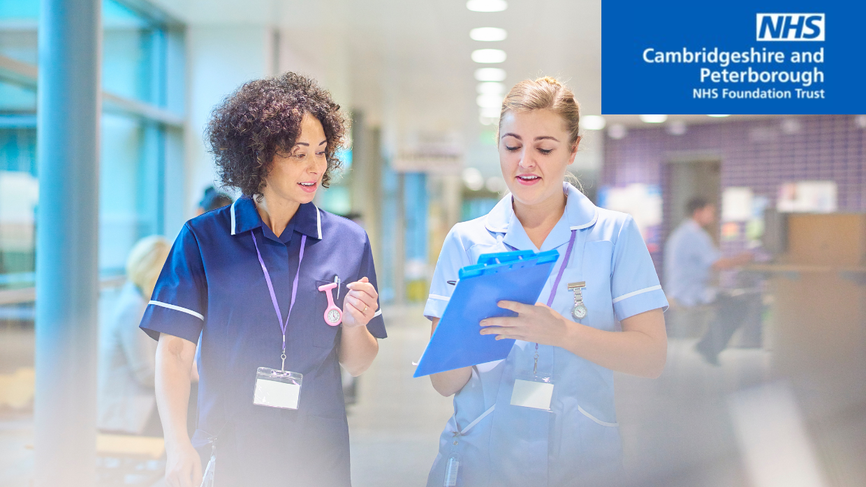 Two nurses walking through a hospital looking at a clipboard