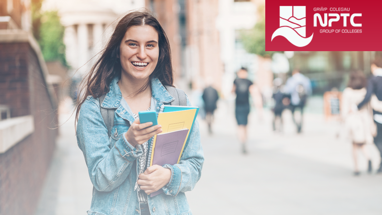 Student smiling carrying books and a mobile phone